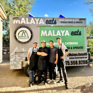 Malaya Eats' team smiling and standing in front of their food truck. There are four men posed together in their Malaya Eats uniforms.